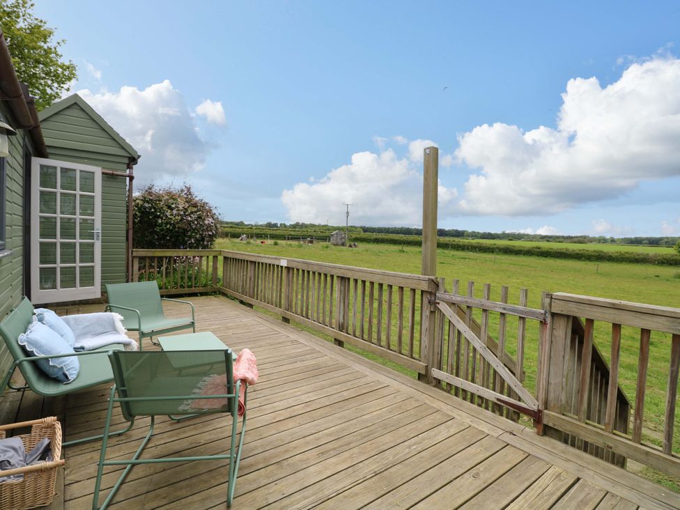 A deck with chairs and a shed at Hollyhock in King's Lynn