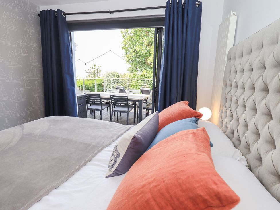 A bedroom with a bed and outdoor seating visible at Yonder Lea Bowness-On-Windermere