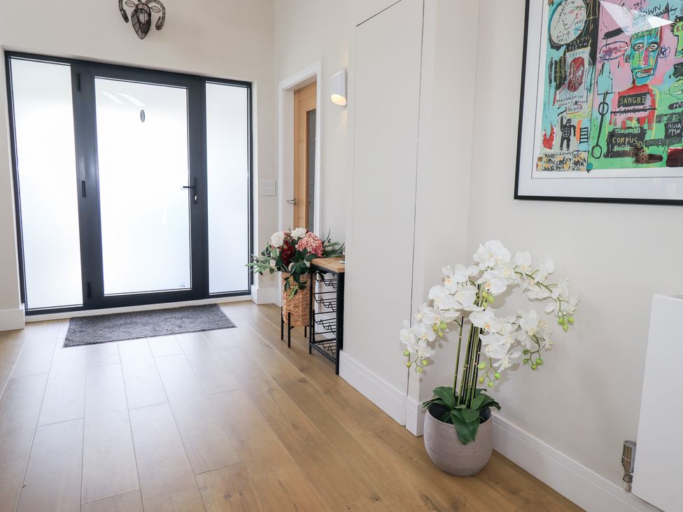 A hallway with a front door and flower arrangement at Yonder Lea in Bowness-On-Windermere