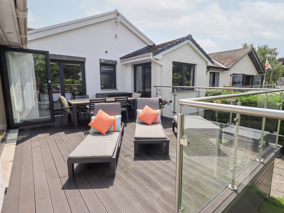A deck area with lounge chairs and a dining table at Yonder Lea Bowness-On-Windermere
