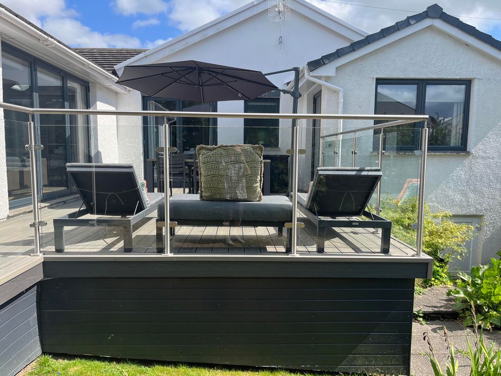 An outdoor patio with chairs and an umbrella at Yonder Lea in Bowness-On-Windermere