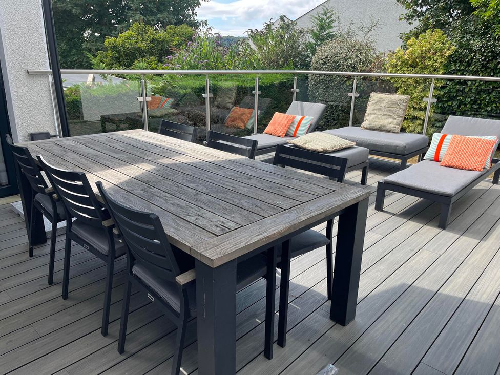 An outdoor patio with a dining table and loungers at Yonder Lea Bowness-On-Windermere