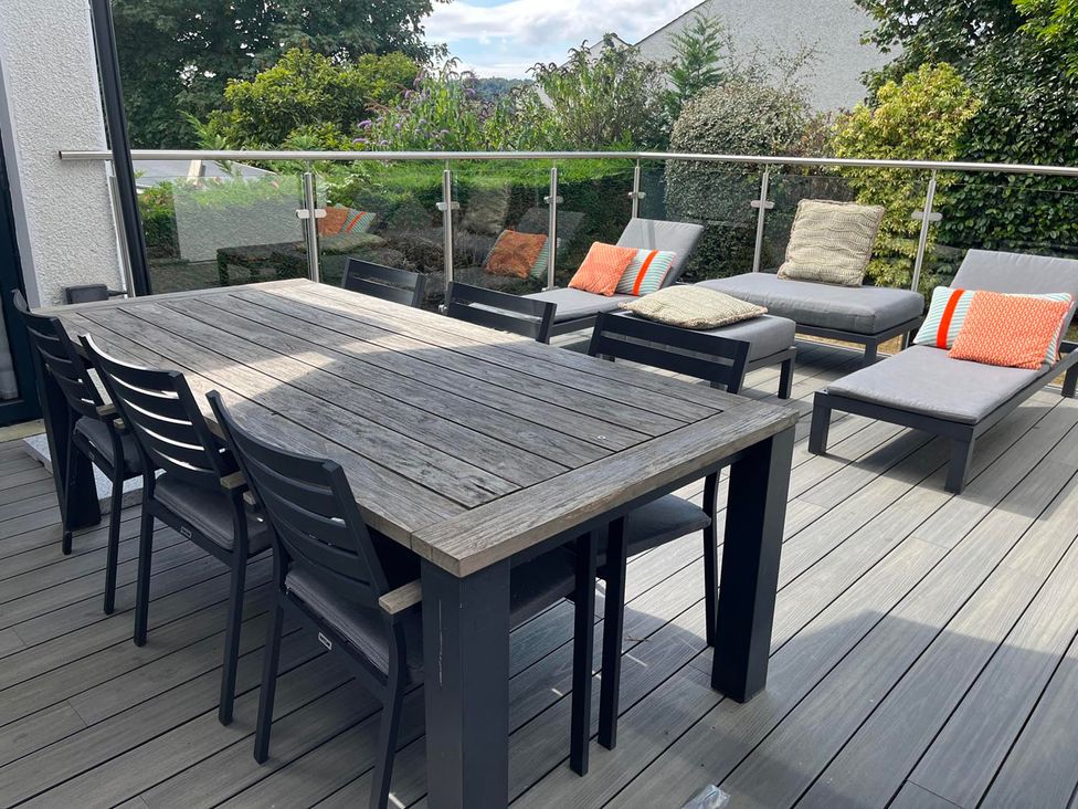 An outdoor patio with a wooden table and chairs at Yonder Lea Bowness-On-Windermere