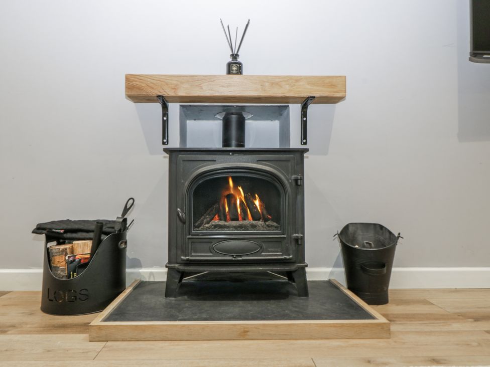 A wood stove with a shelf and log basket in Ranbir House Longhope