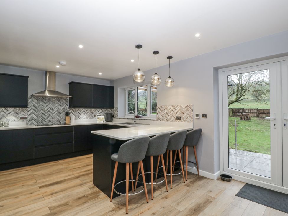 A kitchen with an island and stools at Ranbir House, Longhope