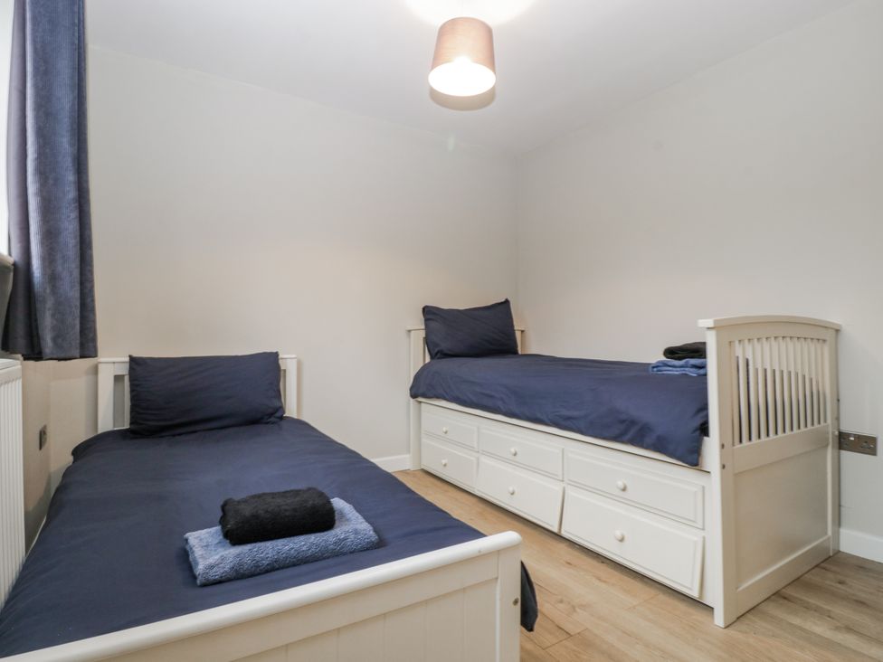 A bedroom with two beds and a nightstand at Ranbir House in Longhope