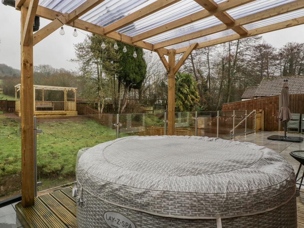 A hot tub on a wooden deck in a garden at Ranbir House in Longhope