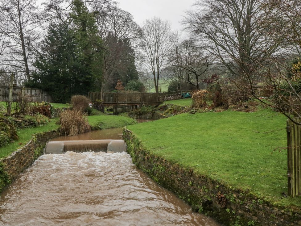 A garden with a stream flowing through it at Ranbir House in Longhope