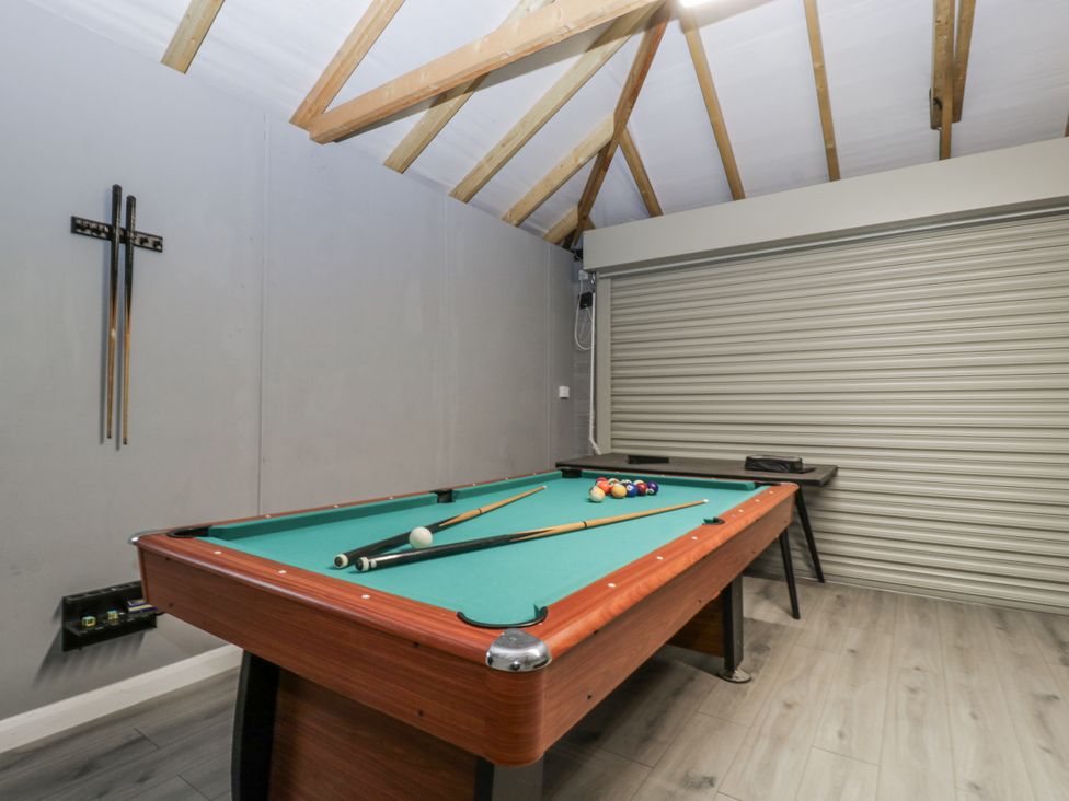 A pool table with cue sticks and a wall rack in a recreation room at Ranbir House Longhope
