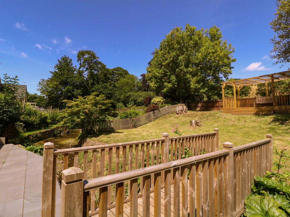 A garden with a fenced area and wooden decking at Ranbir House in Longhope