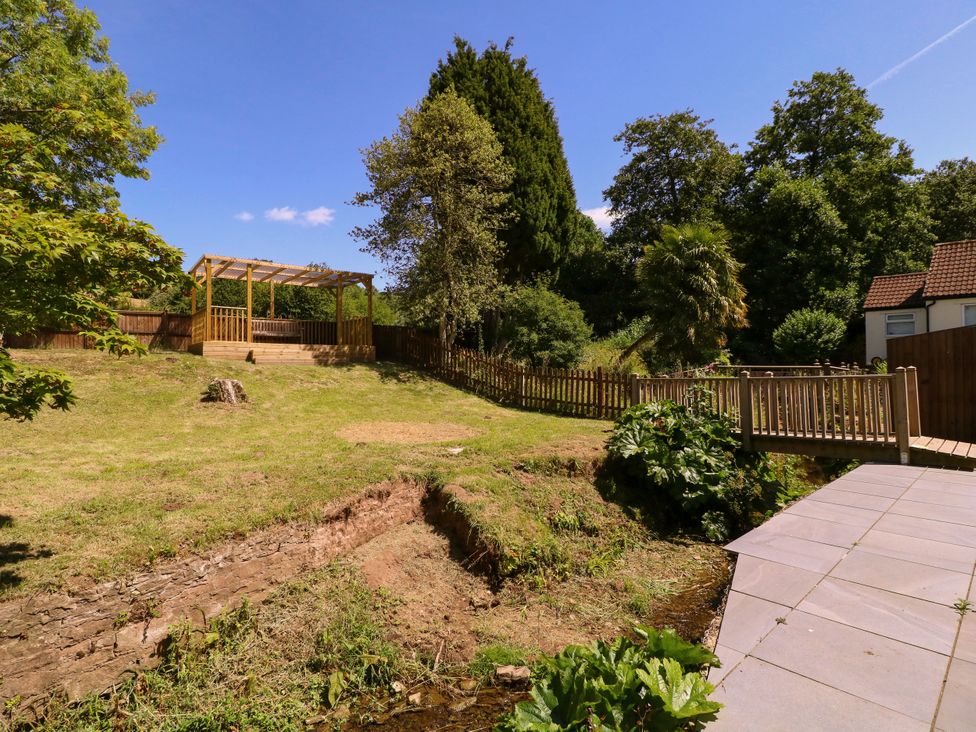 A garden with a wooden deck and a stream at Ranbir House in Longhope
