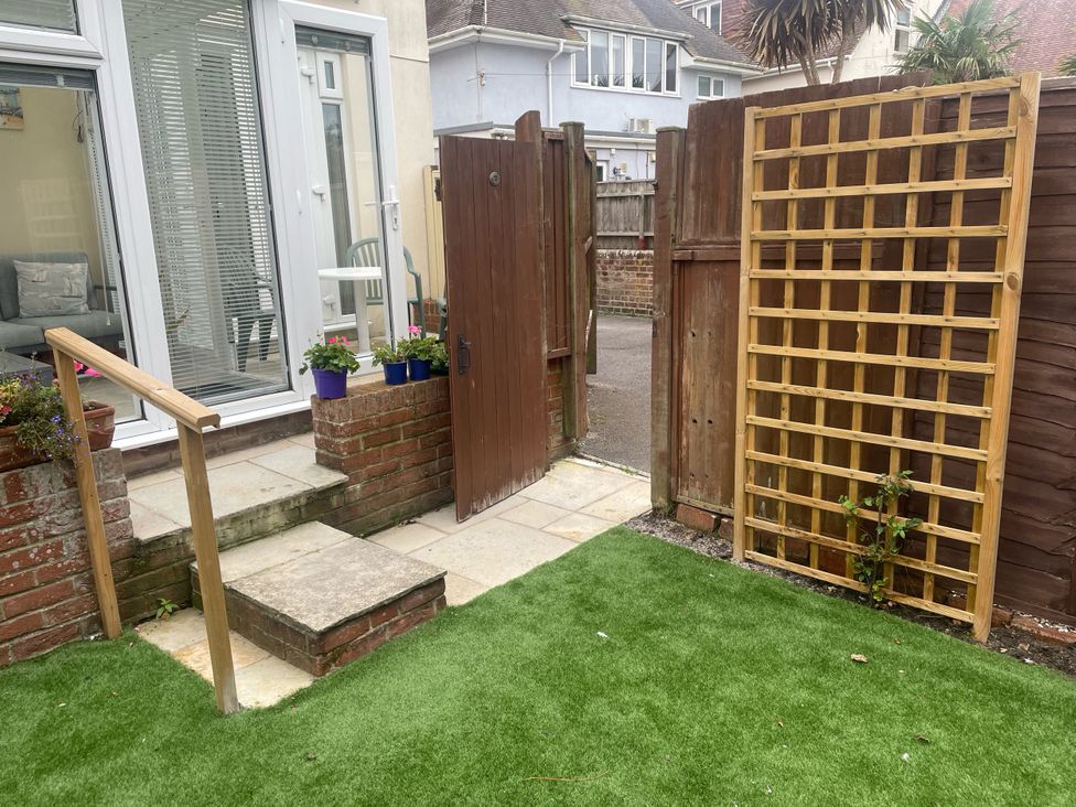 A garden with a gate and stepping stones at Sandy Haven in Swanage