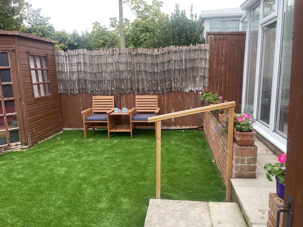A garden with chairs and a wooden shed at Sandy Haven in Swanage