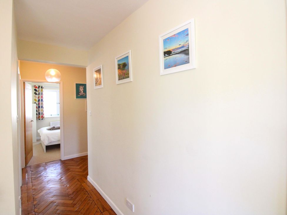A hallway with framed photos and a light fixture at Tansea in Hope Cove