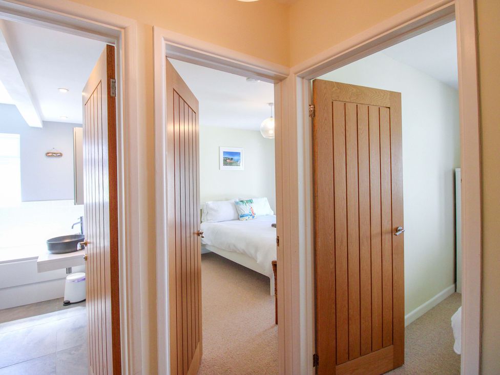 A hallway with doors leading to a bedroom and a bathroom at Tansea in Hope Cove