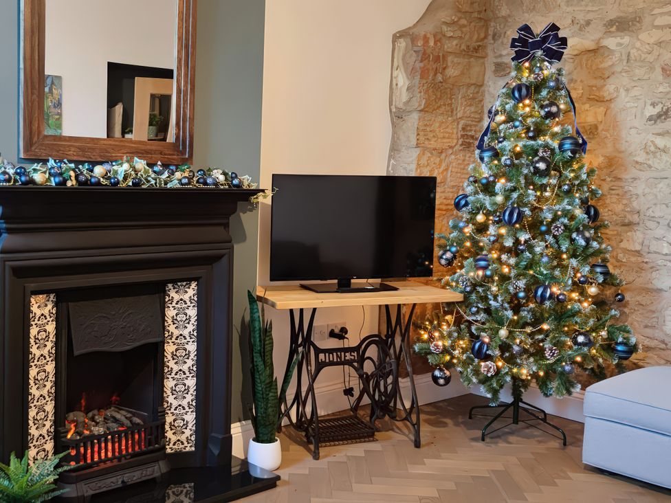 A living room with a Christmas tree and a fireplace at Courthouse Cottage in Eckington, Derbyshire