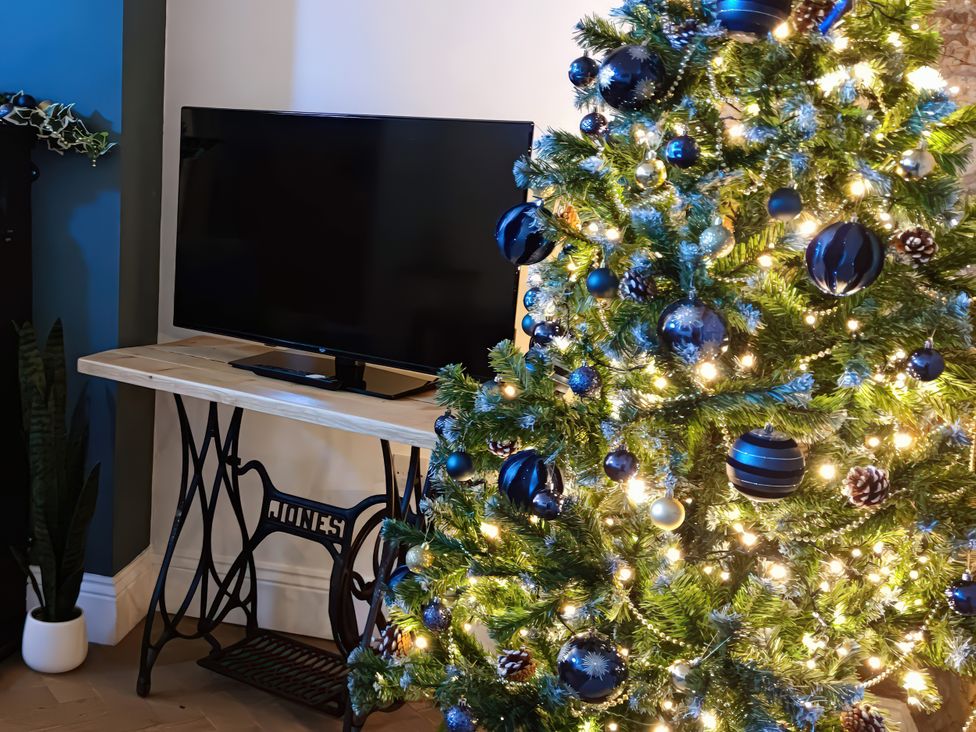 A living room with a Christmas tree and a television at Courthouse Cottage in Eckington, Derbyshire