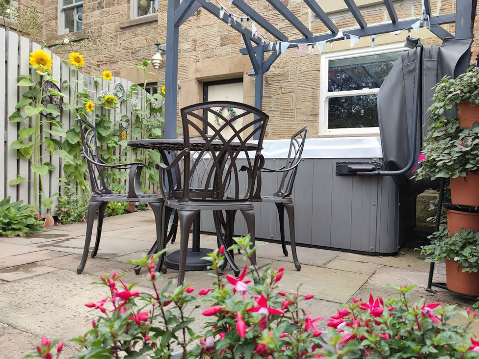 A garden with a table and chairs and a hot tub at Courthouse Cottage in Eckington, Derbyshire