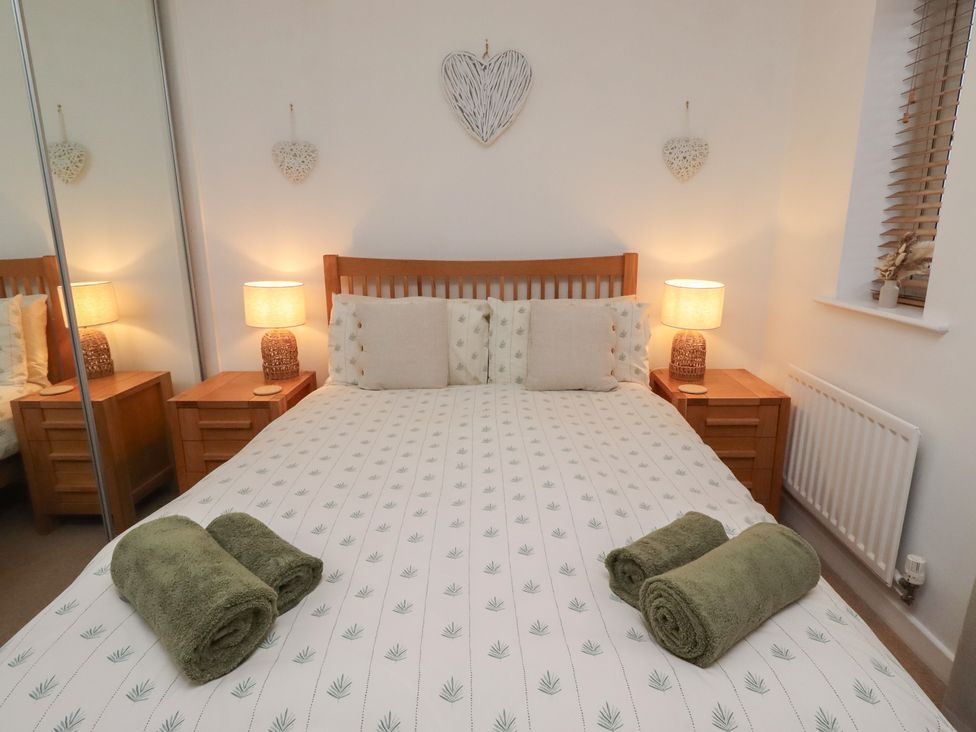 A bedroom with a bed and bedside tables at Brucap Cottage Beadnell
