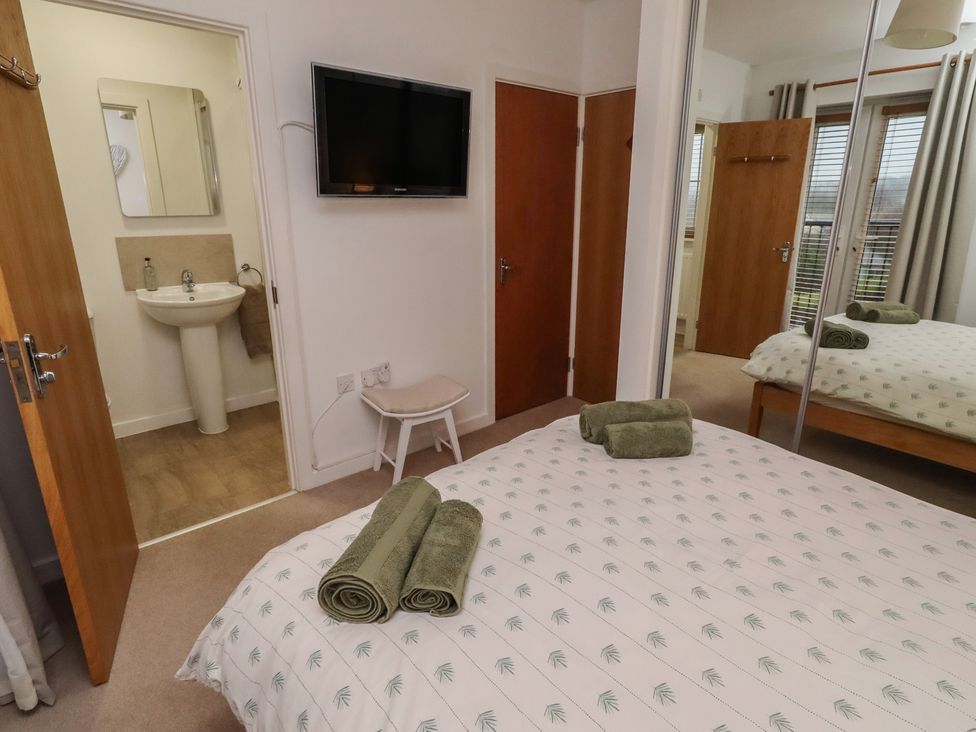 A bedroom with a bed and mirror at Brucap Cottage in Beadnell