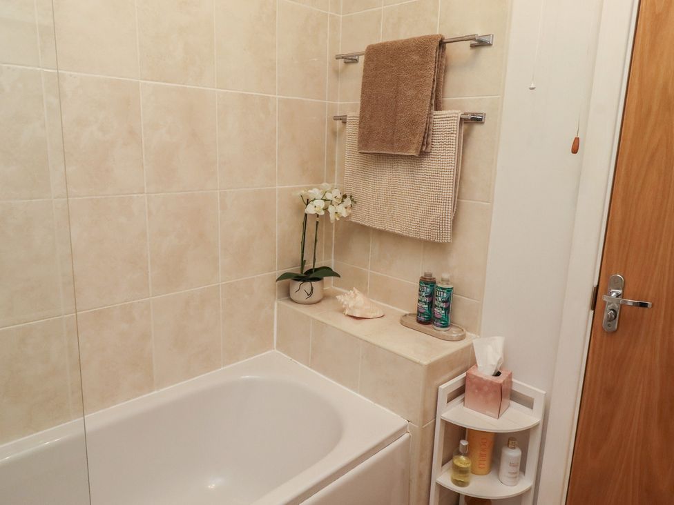 A bathroom with a bathtub, towels, and toiletries at Brucap Cottage in Beadnell