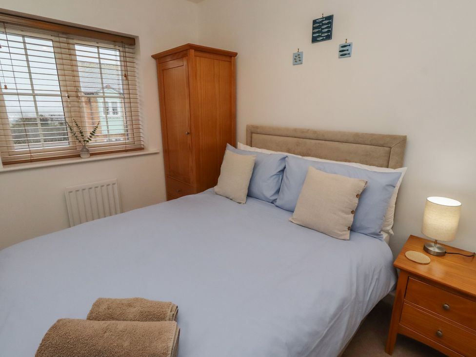 A bedroom with a bed and wardrobe at Brucap Cottage Beadnell