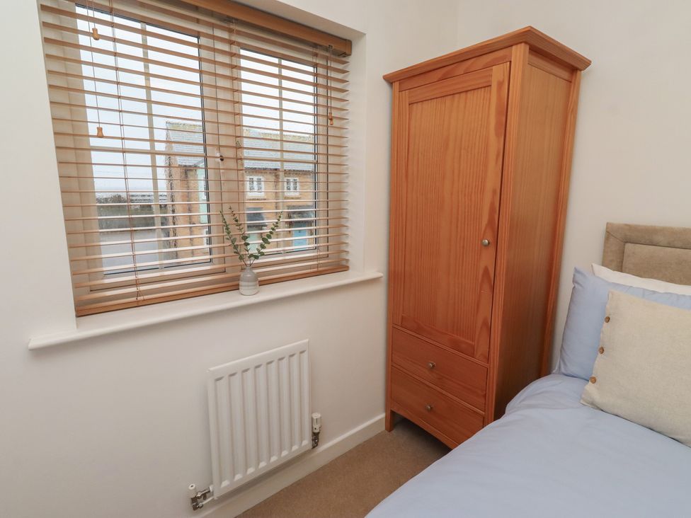 A bedroom with a window and a wardrobe at Brucap Cottage Beadnell