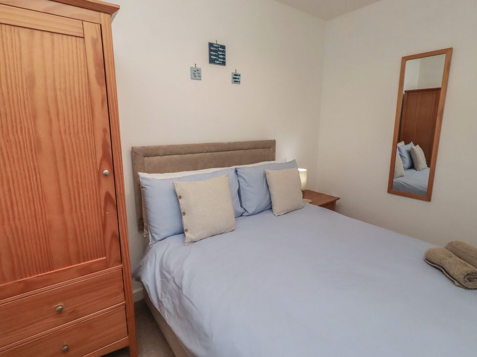 A bedroom with a bed and wardrobe at Brucap Cottage Beadnell