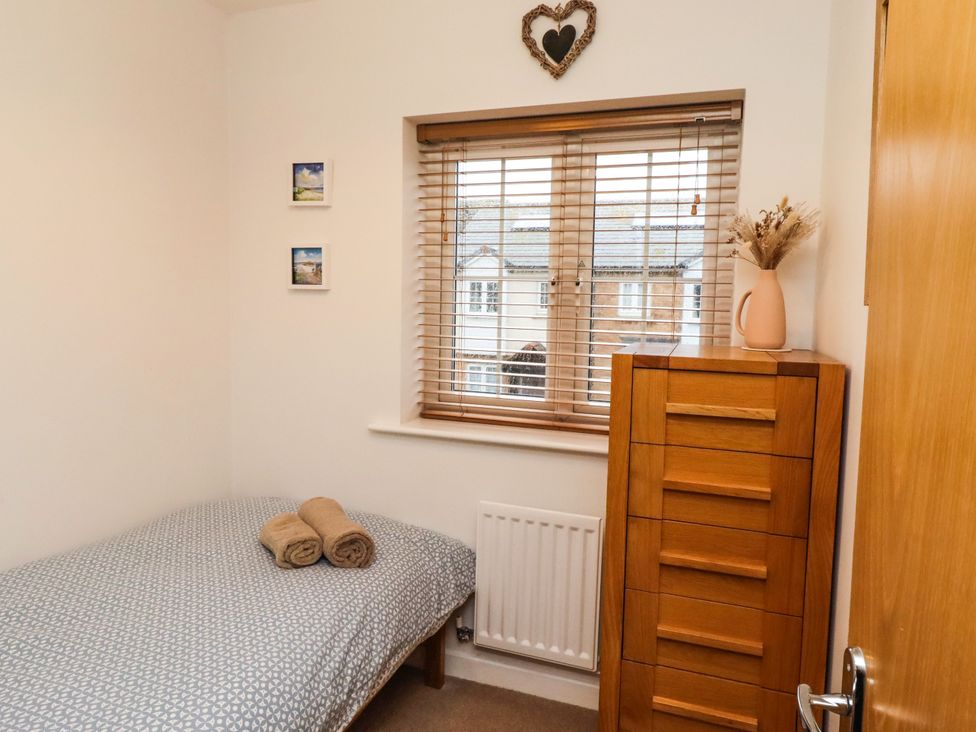 A bedroom with a bed and chest of drawers at Brucap Cottage in Beadnell