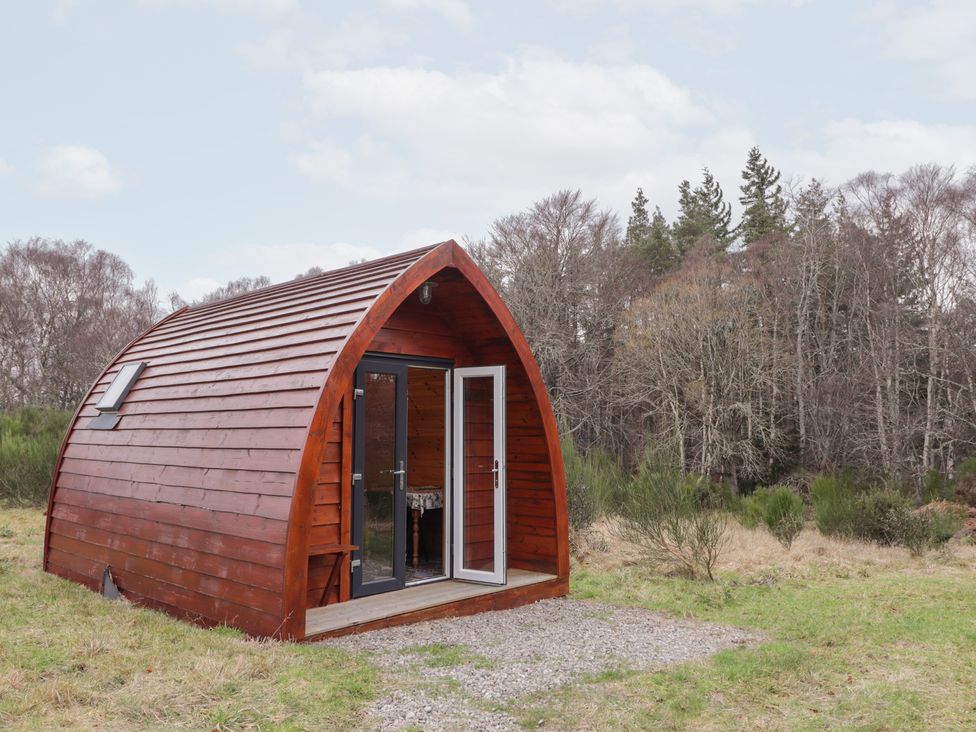 A wooden cabin with a door and windows in a natural setting at Pod 1