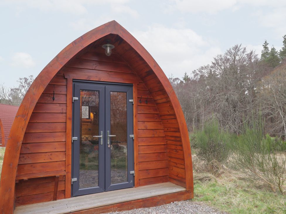 An outdoor view of a wooden pod entrance at Pod 1