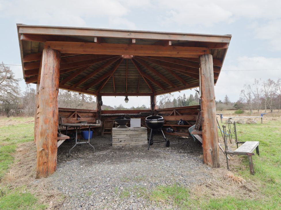 An outdoor shelter with a grill and seating area at Pod 1