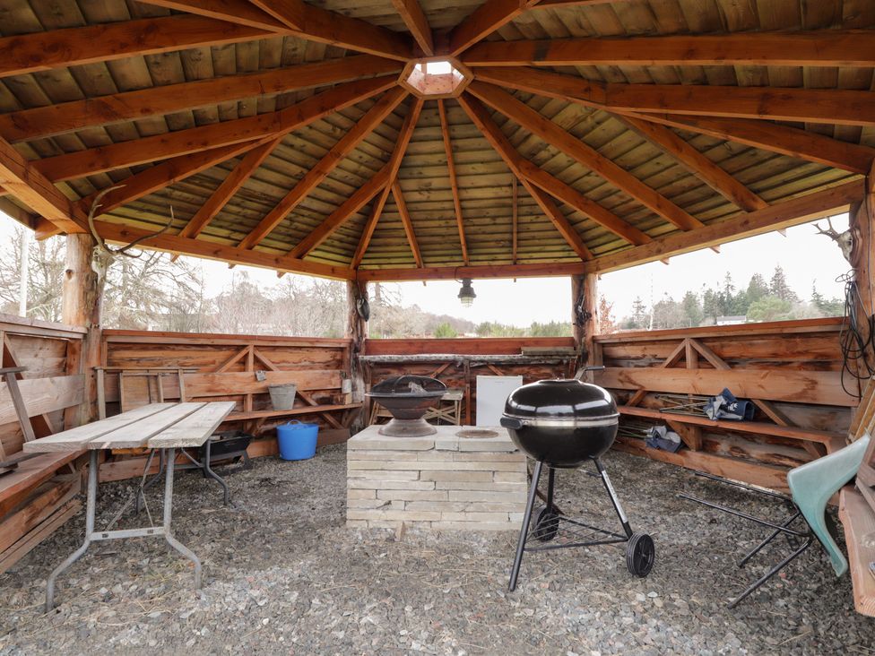 An outdoor shelter with a table and barbecue grill at Pod 1