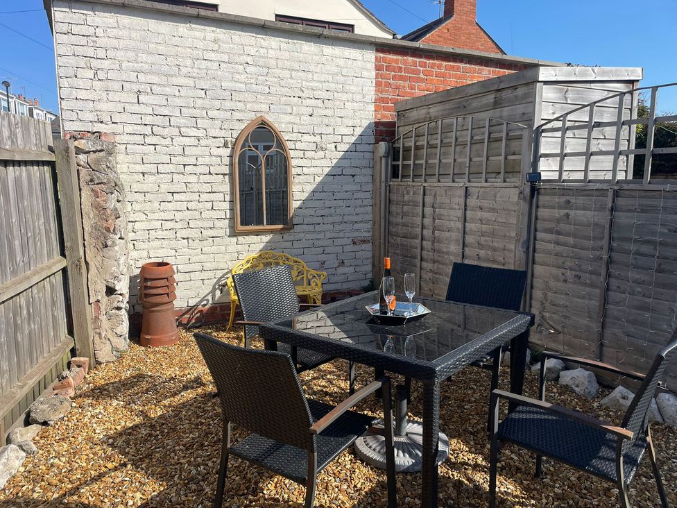A garden with a table and chairs at Winkle Cottage in Weymouth