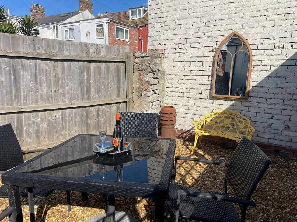 A garden with a table and chairs at Winkle Cottage in Weymouth