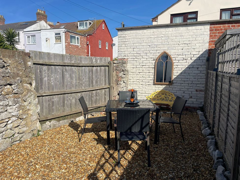 An outdoor area with a table and chairs at Winkle Cottage in Weymouth
