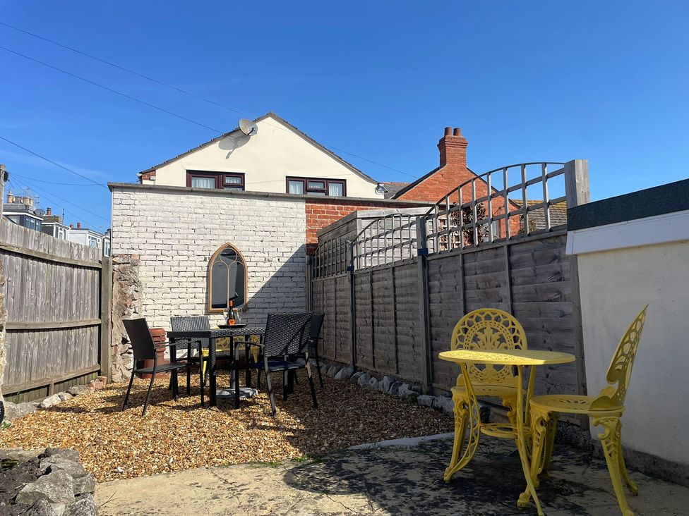 A garden with a table and chairs at Winkle Cottage in Weymouth