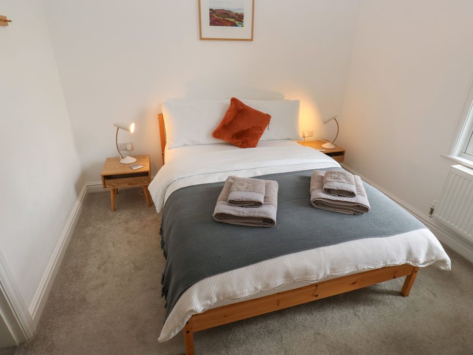 A bedroom with a bed, bedside table, lamp, and towels at Potter’s Cottage Fulwood near Sheffield