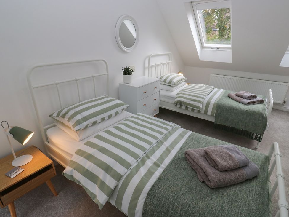 A bedroom with two beds and a nightstand at Potter’s Cottage in Fulwood near Sheffield