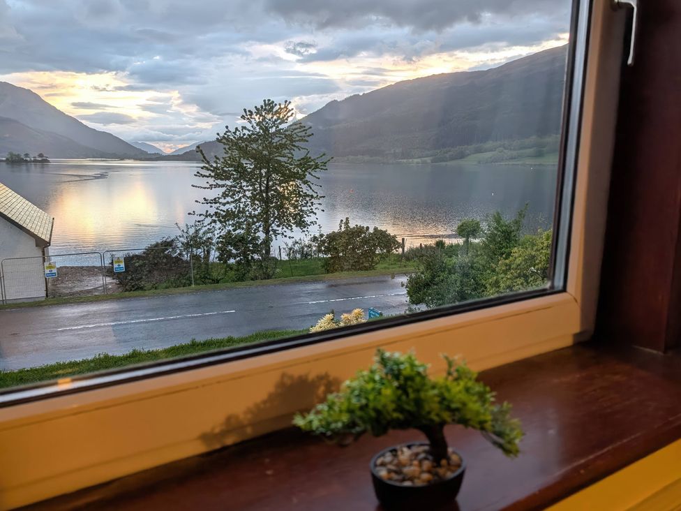 A window view overlooking a lake and mountains at Callart View in Glencoe