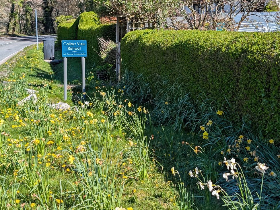 A sign for Callart View Retreat with flowers and grass at Callart View, Glencoe
