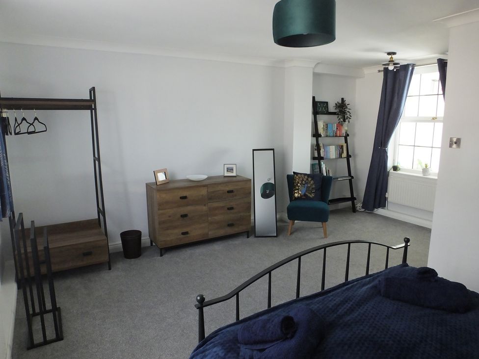 A bedroom featuring a bed, chest of drawers, and a clothes rack at 1 Ilsham Cottages in Torquay