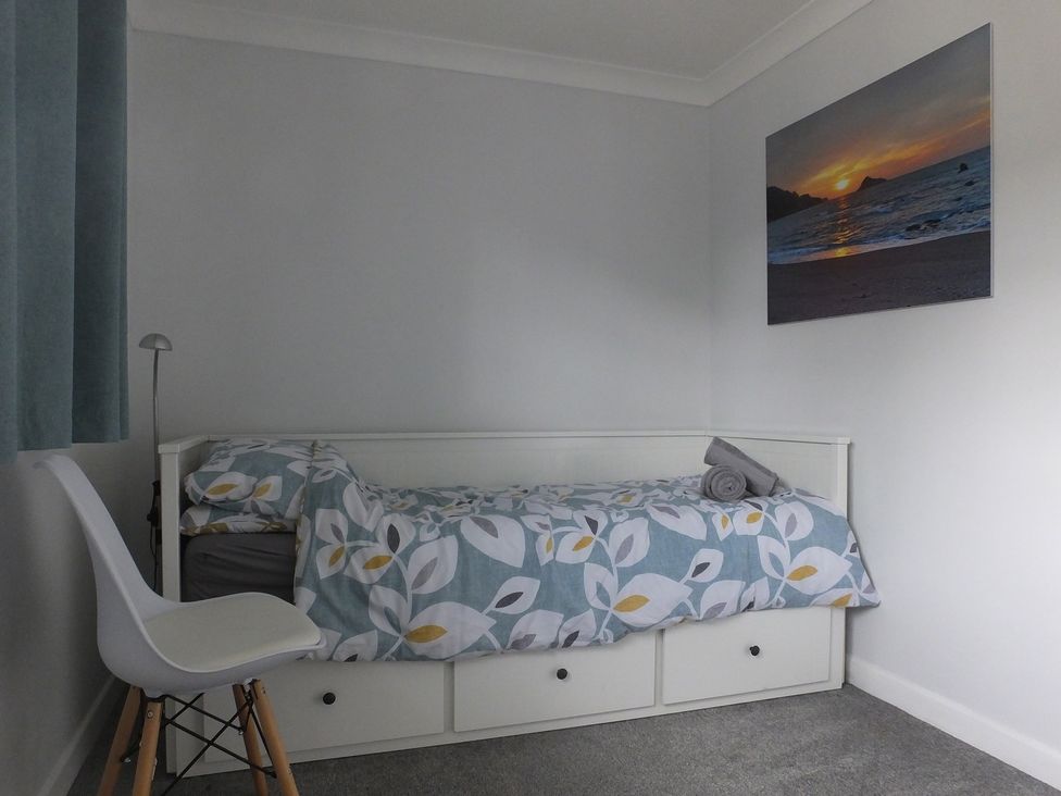 A bedroom with a bed and a chair at 1 Ilsham Cottages in Torquay