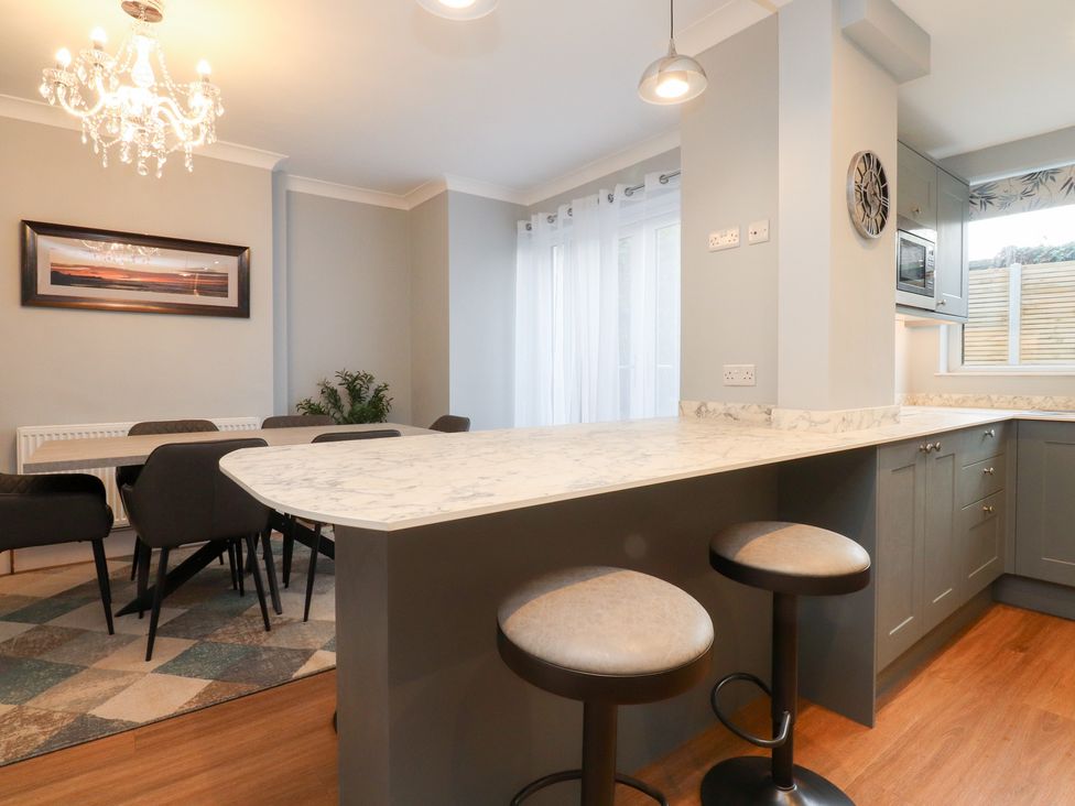A kitchen with a dining area and bar stools at 480 Marine Road East in Morecambe