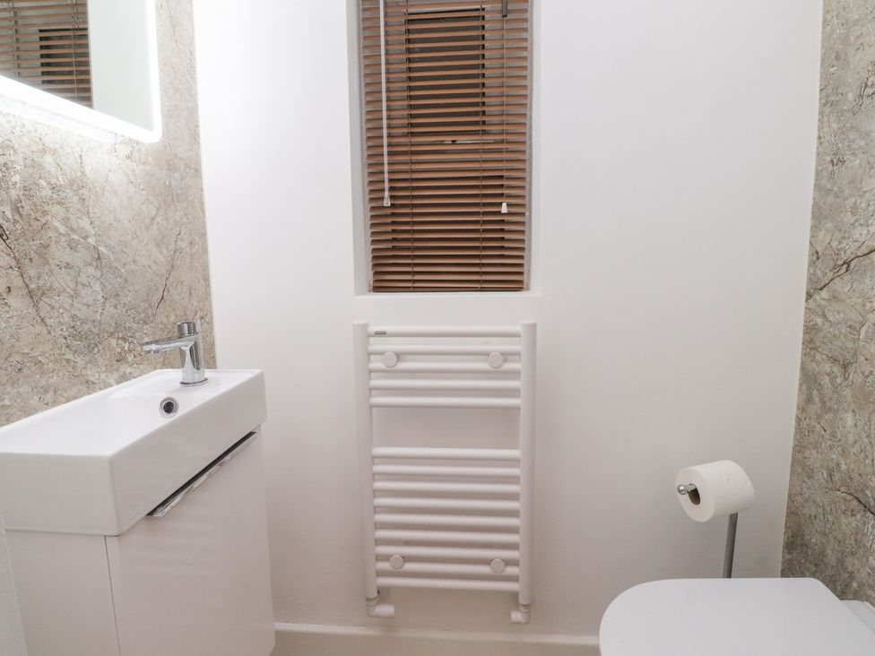 A bathroom with a sink, toilet, towel radiator, and window at 480 Marine Road East Morecambe