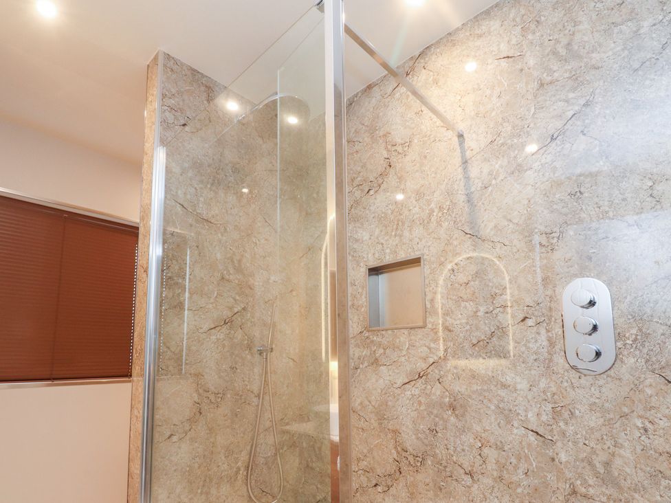 A shower with a glass enclosure and wall tiles at 480 Marine Road East Morecambe