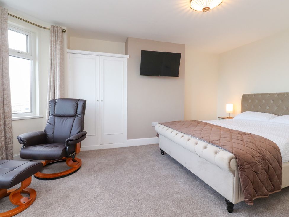 A bedroom with a bed, armchair, and television at 480 Marine Road East in Morecambe
