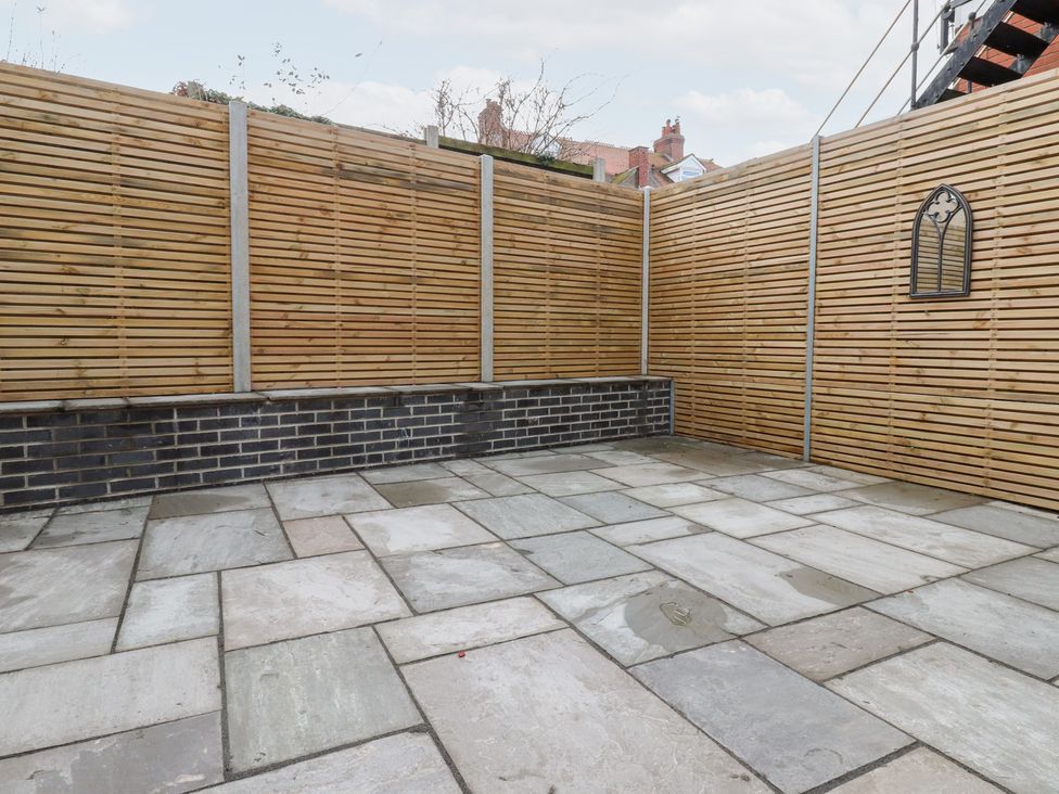 A garden with a stone patio and wooden fencing at 480 Marine Road East in Morecambe
