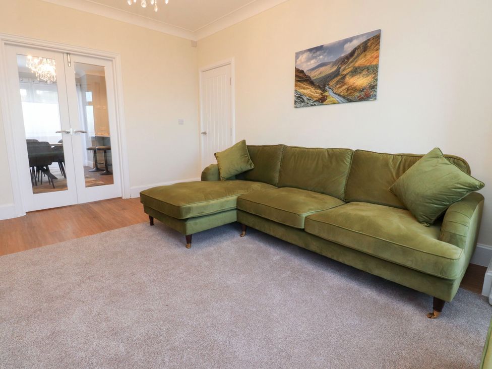 A living room with a green sofa and double doors at Marilyn in Morecambe