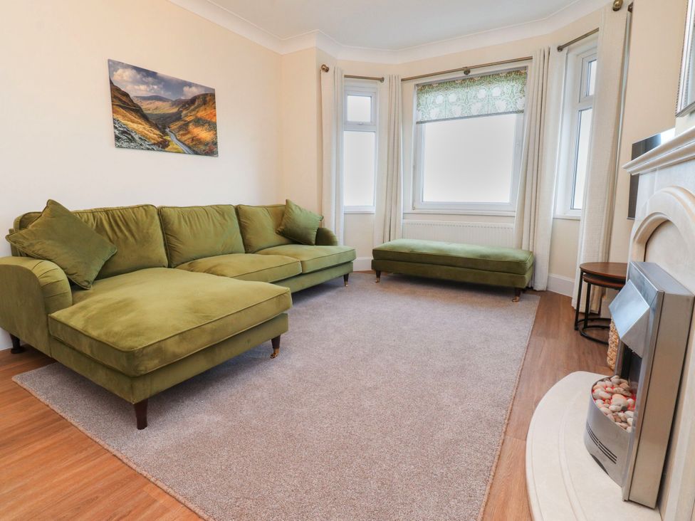 A living room with a green sofa and fireplace at Marilyn in Morecambe